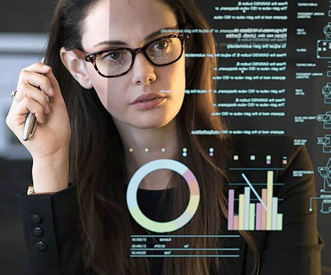 woman with glasses looking at graphs on the screen