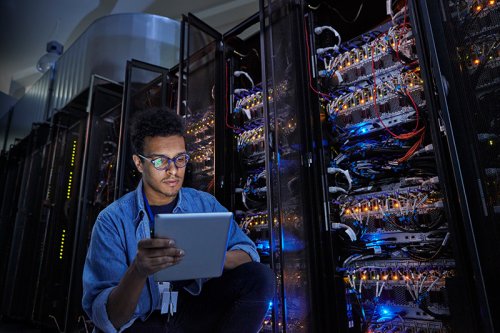 Technician using a tablet next to a server cabinet